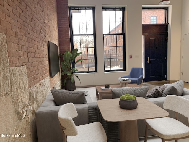 living room featuring brick wall and a wealth of natural light