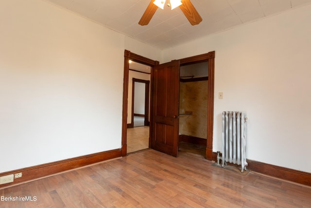 unfurnished room featuring wood-type flooring, radiator, and ceiling fan