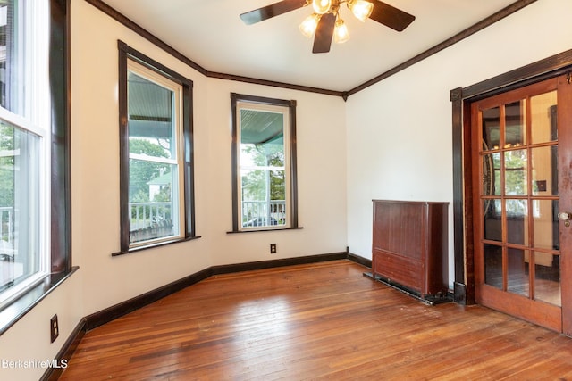 empty room with hardwood / wood-style floors, ceiling fan, ornamental molding, and french doors