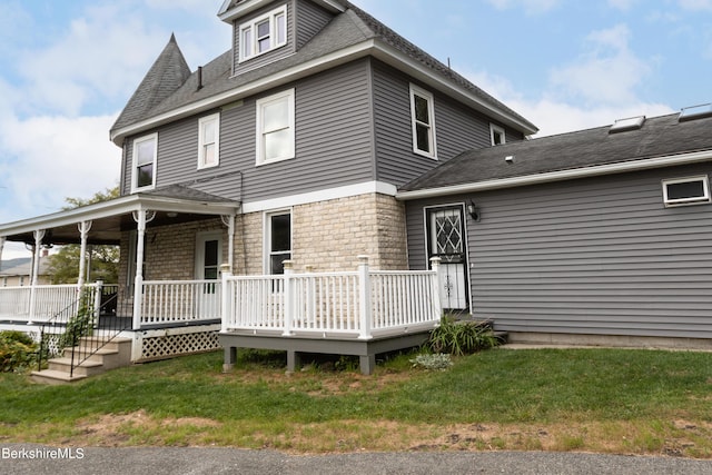 rear view of property featuring a yard and covered porch