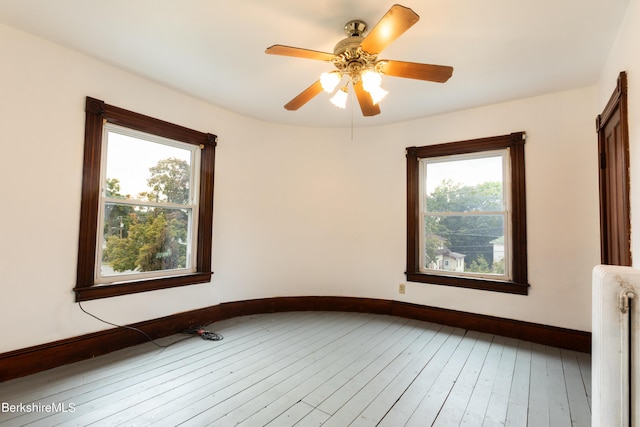 spare room featuring radiator, ceiling fan, and wood-type flooring