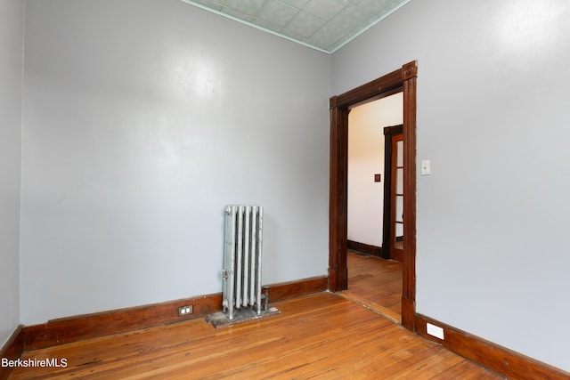 empty room featuring radiator heating unit and light hardwood / wood-style flooring