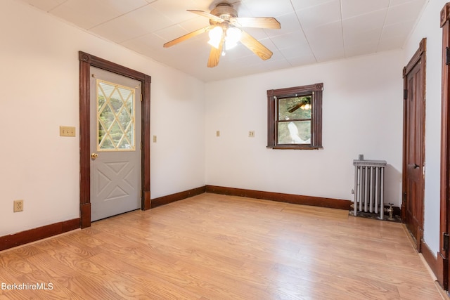 spare room with radiator heating unit, light hardwood / wood-style flooring, and ceiling fan