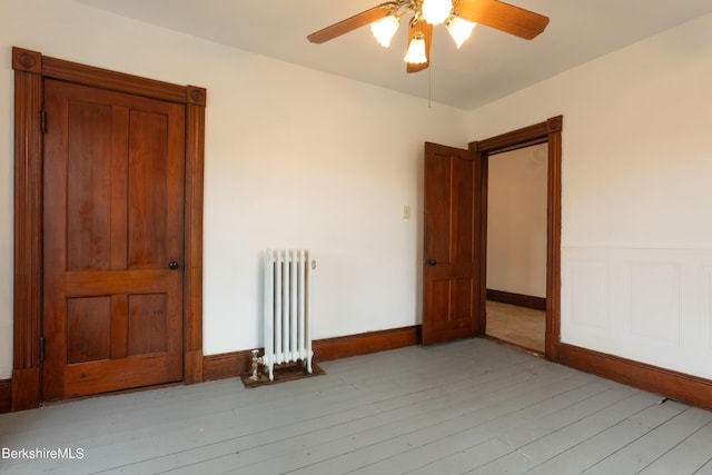 unfurnished room with ceiling fan, light hardwood / wood-style floors, and radiator heating unit