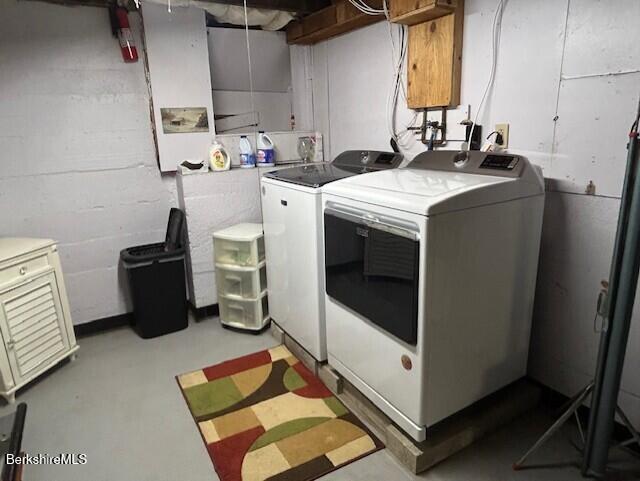 clothes washing area featuring laundry area, washer and clothes dryer, and concrete block wall