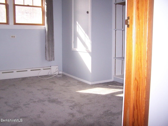 carpeted empty room featuring baseboards, plenty of natural light, and baseboard heating