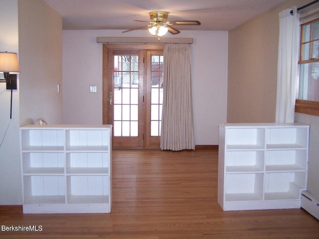 doorway to outside featuring a ceiling fan, a baseboard heating unit, and wood finished floors
