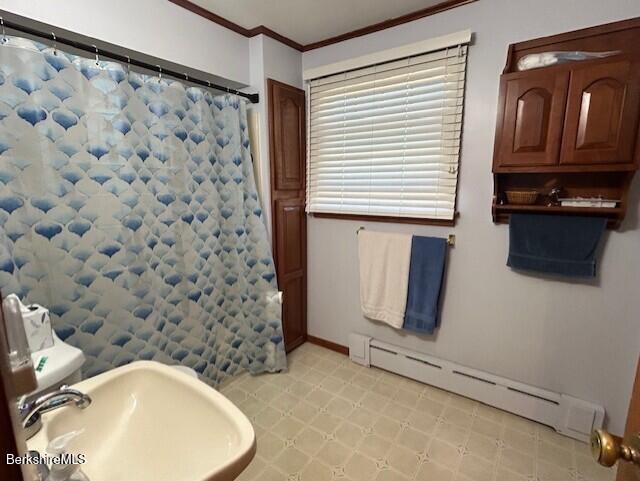 full bathroom featuring crown molding, a baseboard radiator, curtained shower, and a sink