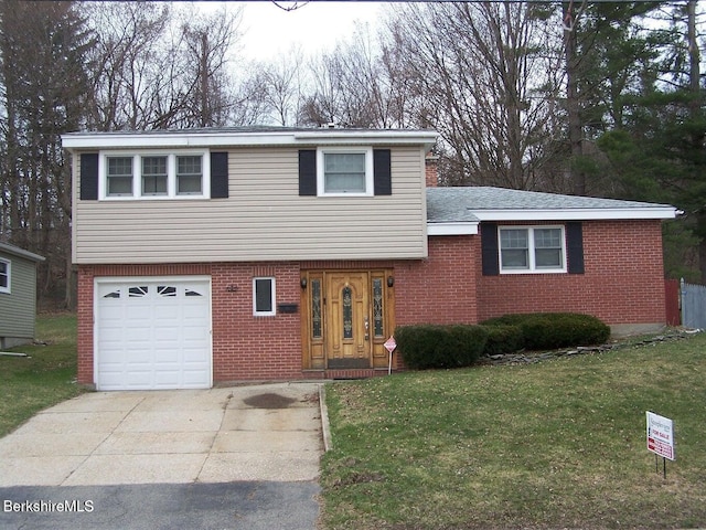 tri-level home with a garage, concrete driveway, a front yard, and brick siding