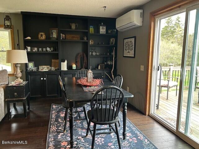 dining area featuring a textured ceiling, a wall mounted AC, dark hardwood / wood-style flooring, and built in shelves