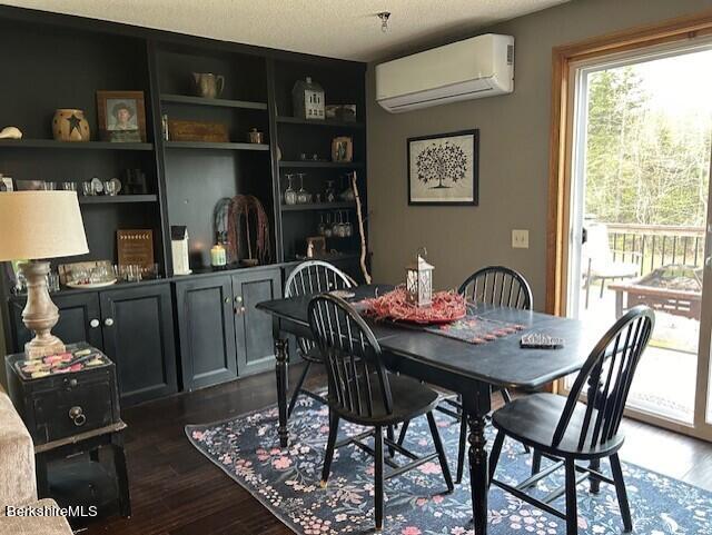 dining area with a wall mounted air conditioner, a textured ceiling, and dark hardwood / wood-style flooring