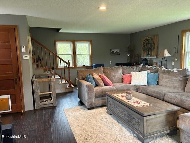 living room featuring dark wood-type flooring and a textured ceiling