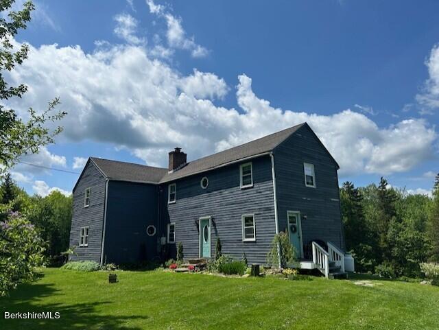 rear view of property featuring a lawn