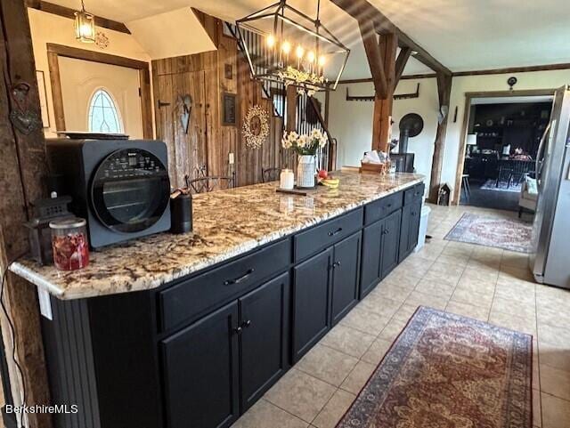 kitchen featuring stainless steel fridge, wooden walls, pendant lighting, and an inviting chandelier