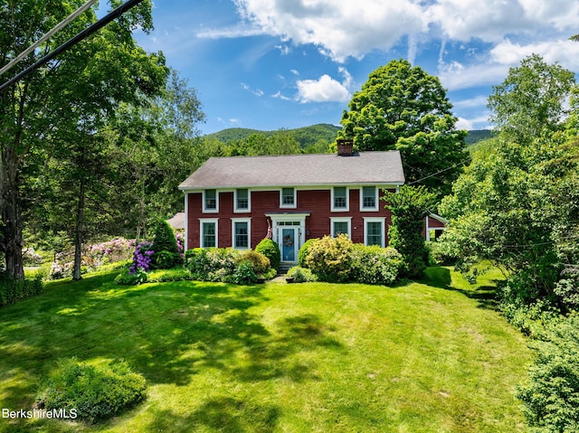 colonial-style house featuring a mountain view and a front lawn