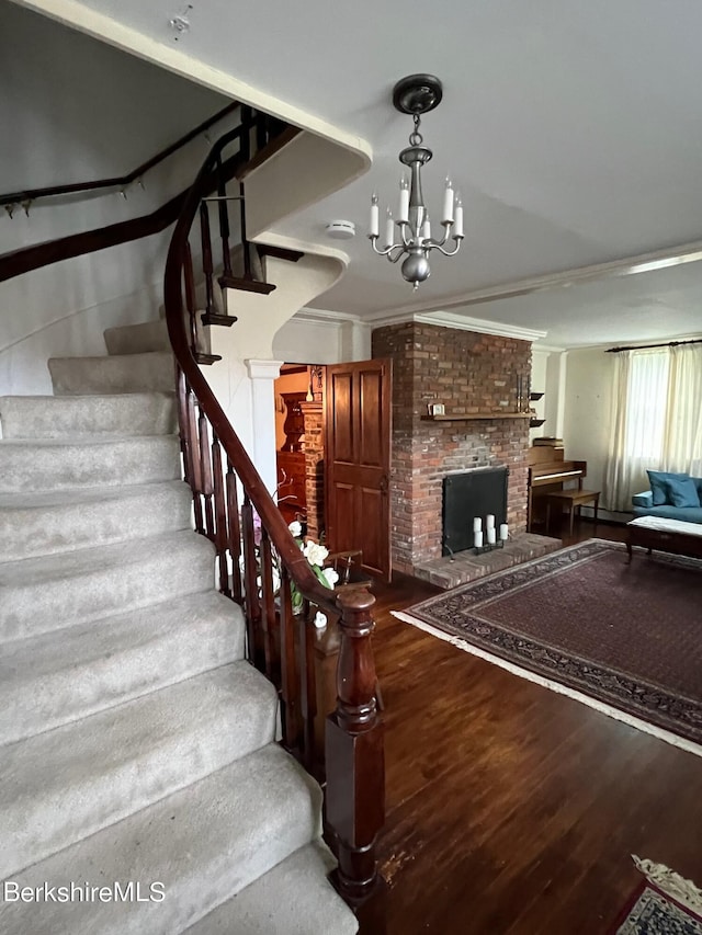 staircase with a chandelier, hardwood / wood-style floors, and ornamental molding