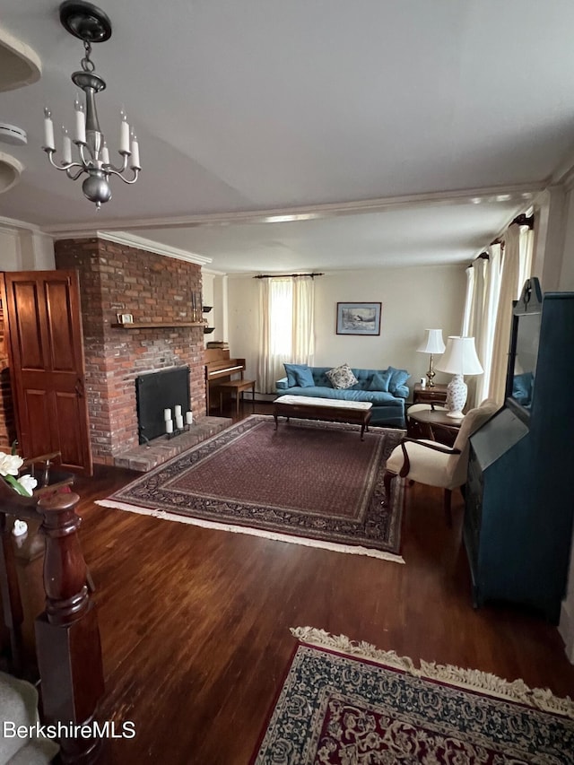 living room with hardwood / wood-style floors, crown molding, a fireplace, and an inviting chandelier