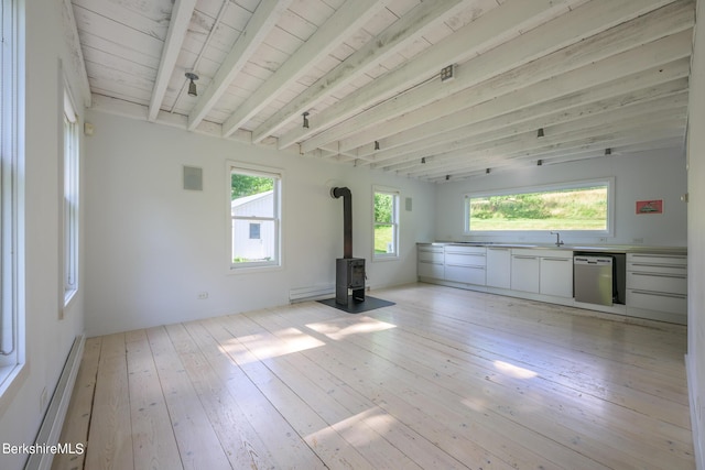 unfurnished living room featuring beamed ceiling, a wood stove, plenty of natural light, and wooden ceiling