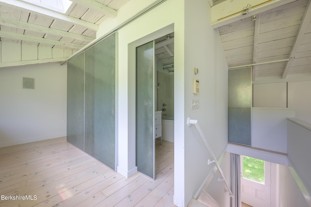 corridor featuring vaulted ceiling with skylight, light hardwood / wood-style floors, and wood ceiling