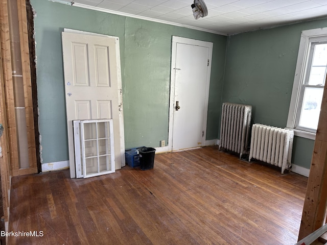 empty room featuring radiator heating unit and dark hardwood / wood-style floors