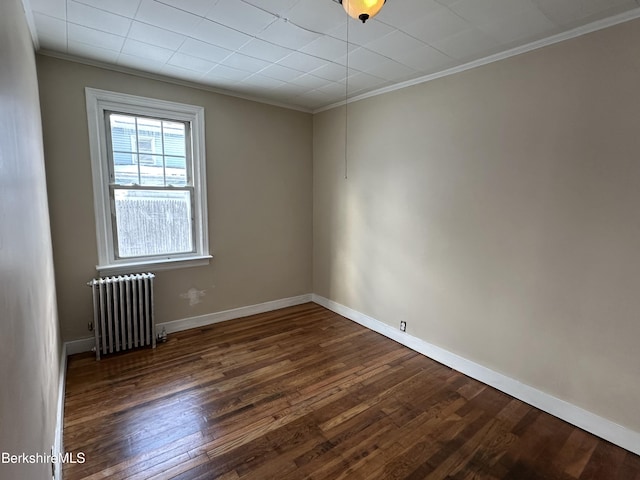 spare room with ornamental molding, radiator heating unit, and dark hardwood / wood-style flooring