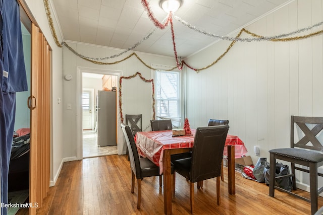 dining space with wood-type flooring, ornamental molding, and a healthy amount of sunlight