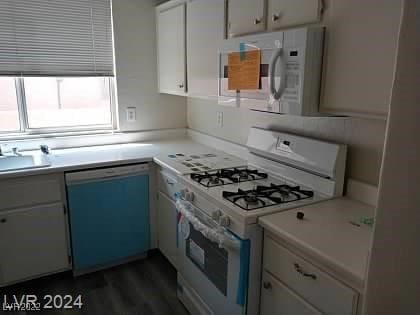 kitchen featuring dark wood-type flooring, white appliances, white cabinetry, and sink