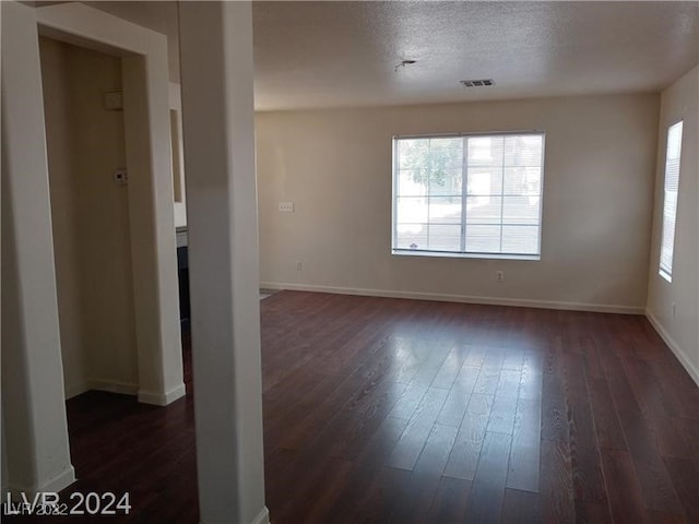 spare room featuring dark hardwood / wood-style floors and a textured ceiling