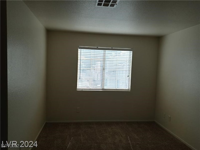 carpeted empty room with a textured ceiling