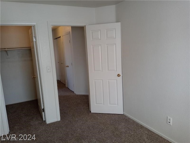 unfurnished bedroom with a closet, a walk in closet, and carpet flooring