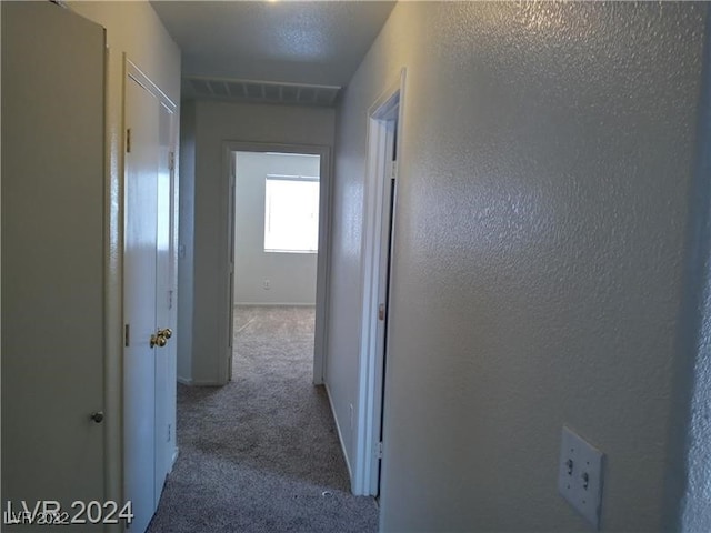 hall with a textured ceiling and carpet