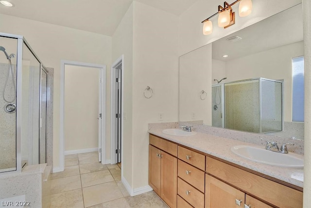 bathroom featuring a shower with shower door, dual sinks, large vanity, and tile floors