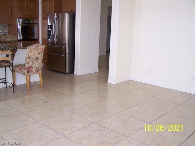 kitchen with light tile floors, appliances with stainless steel finishes, backsplash, and stone countertops