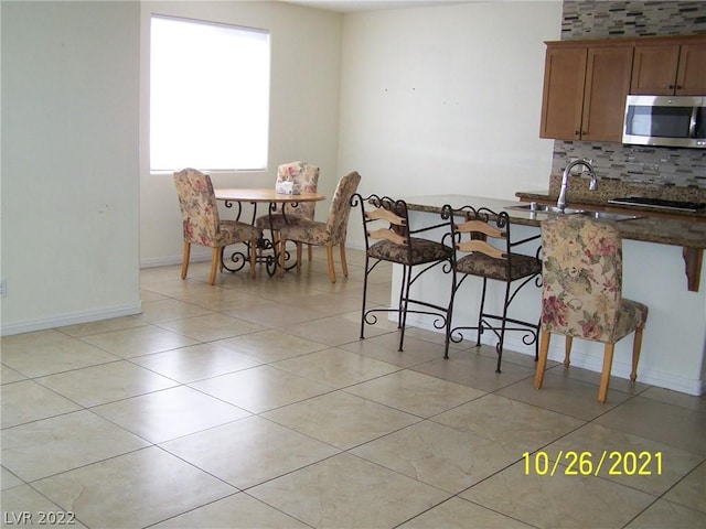 kitchen featuring backsplash, sink, and light tile floors