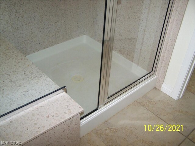 bathroom with tile flooring and a shower with shower door