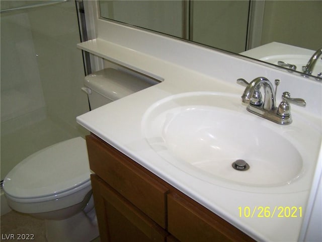 bathroom with toilet, large vanity, and tile floors