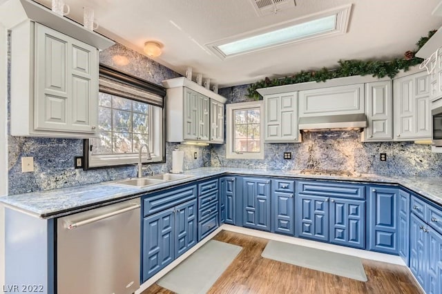 kitchen with appliances with stainless steel finishes, light hardwood / wood-style flooring, sink, and backsplash