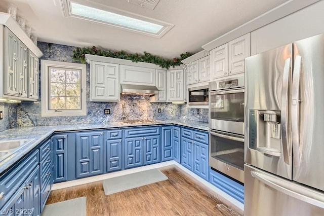 kitchen featuring appliances with stainless steel finishes, backsplash, light wood-type flooring, and white cabinets