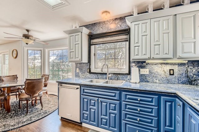 kitchen featuring blue cabinetry, ceiling fan, dishwasher, hardwood / wood-style flooring, and sink