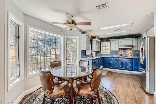 dining space featuring a wealth of natural light, a skylight, light hardwood / wood-style flooring, and ceiling fan