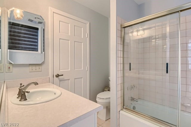 full bathroom with tile flooring, vanity, toilet, and bath / shower combo with glass door