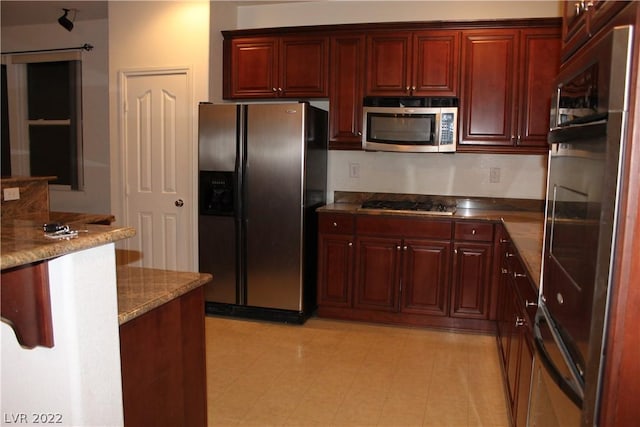 kitchen with appliances with stainless steel finishes, stone countertops, and light tile floors