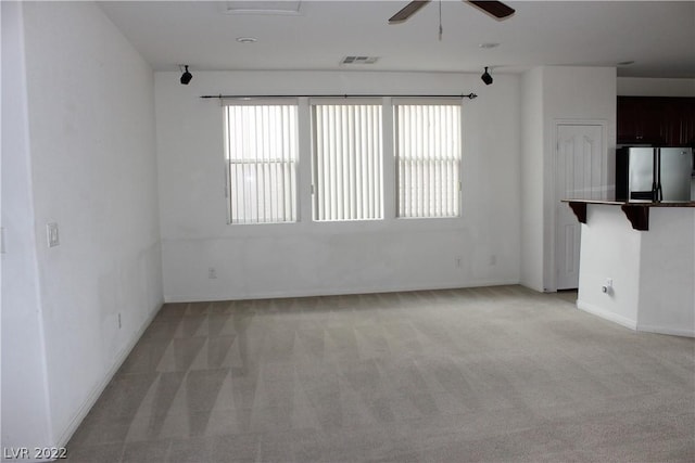 unfurnished room featuring plenty of natural light, ceiling fan, and light colored carpet