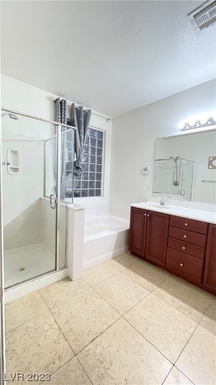 bathroom with a textured ceiling, vanity, plus walk in shower, and tile flooring