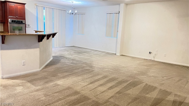 spare room featuring a notable chandelier and light colored carpet