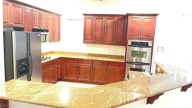 kitchen featuring a breakfast bar area, light stone countertops, stainless steel appliances, and kitchen peninsula