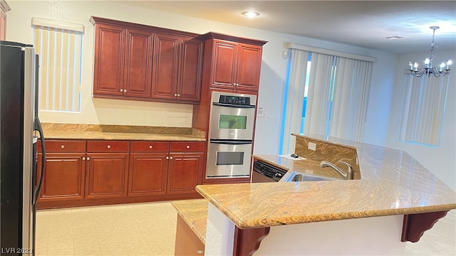 kitchen with sink, light stone counters, a kitchen breakfast bar, a chandelier, and stainless steel appliances