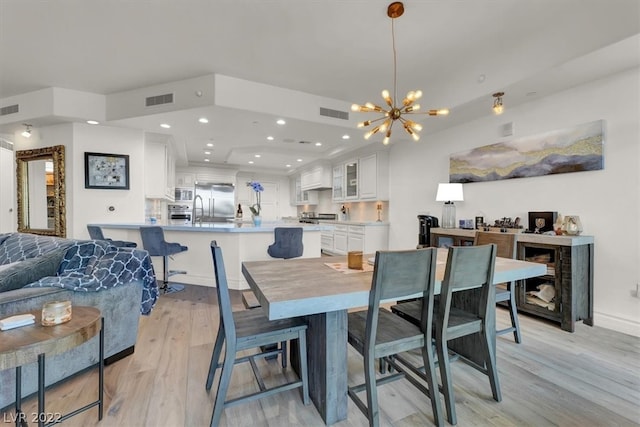 dining space with an inviting chandelier and light hardwood / wood-style flooring