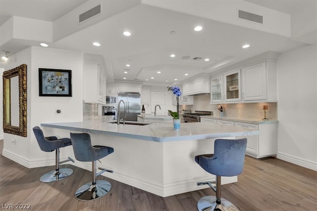 kitchen with a kitchen bar, light hardwood / wood-style flooring, and white cabinetry