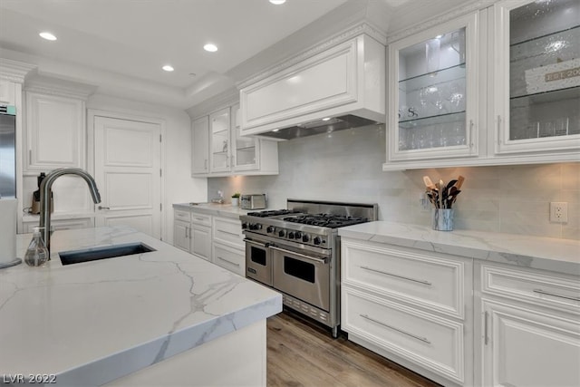 kitchen featuring light hardwood / wood-style floors, white cabinetry, range with two ovens, and light stone counters